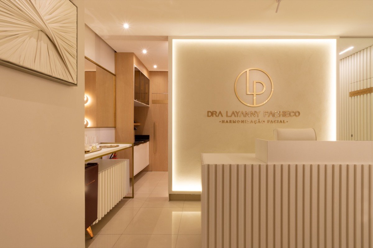 Recepção de clínica com balcão branco e logotipo iluminado