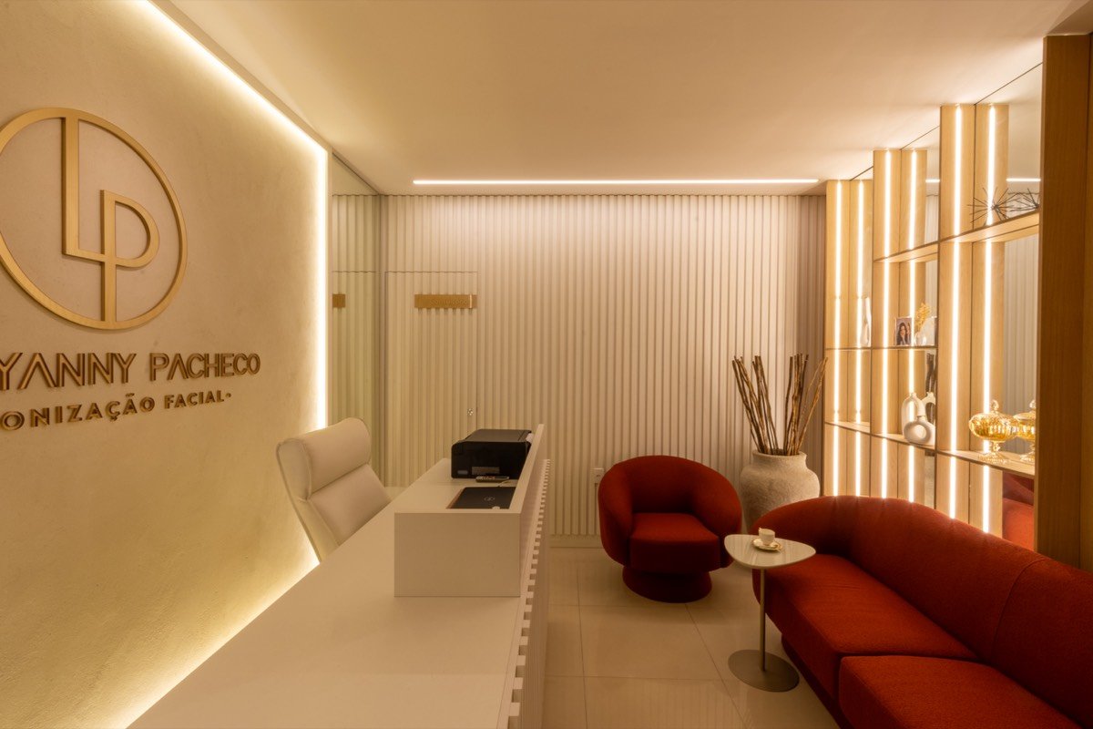 Recepção de clínica com sofá vermelho, madeira clara e luz indireta