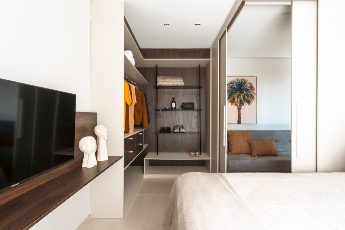 Quarto com marcenaria escura e closet aberto