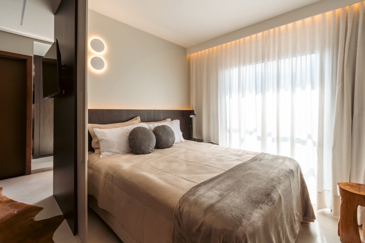 Quarto com cortina de linho, cabeceira em madeira e luz natural